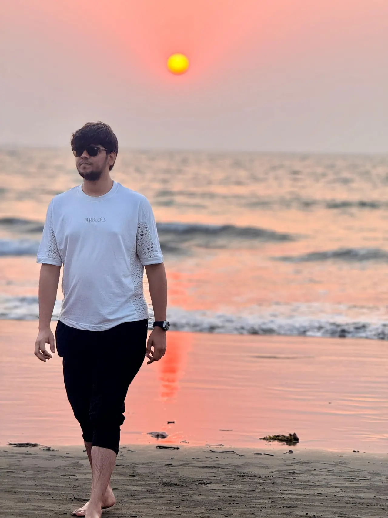 Aditya walking along a beach at sunset